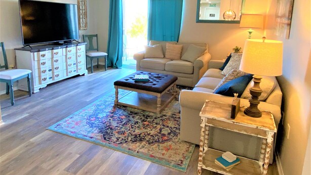 Een woonkamer met een televisie, bank, salontafel en een lamp.