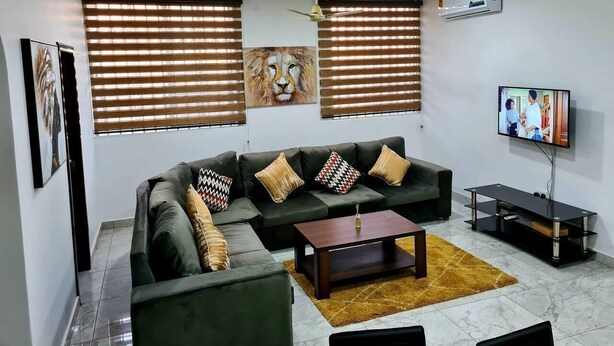 Ein modernes Wohnzimmer mit einem Ecksofa, einem Couchtisch und einem Flachbildfernseher.