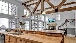 A spacious kitchen with large windows, wooden beams, and a fireplace. - Lakefront Oasis near Lewiston & Niagara Falls (Wilson)