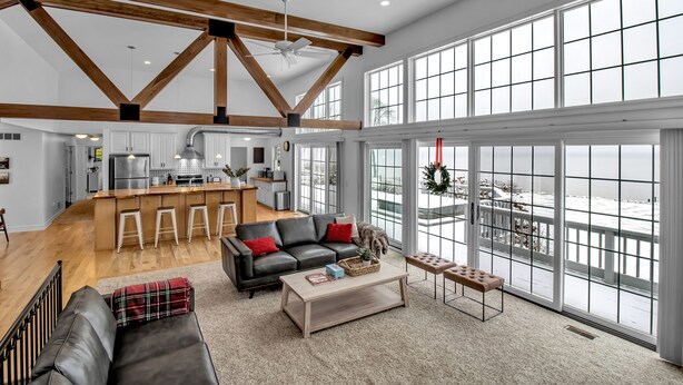 A spacious living area with a kitchen, large windows, and a balcony. - Lakefront Oasis near Lewiston & Niagara Falls (Wilson)
