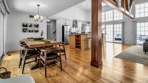 A spacious kitchen with a central island, wooden dining table with chairs, and large windows providing natural light. - Lakefront Oasis near Lewiston & Niagara Falls (Wilson)