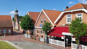 Een traditioneel Europees gebouw met een rode pannendak, een klokkentoren en een bordje dat een restaurant aangeeft.