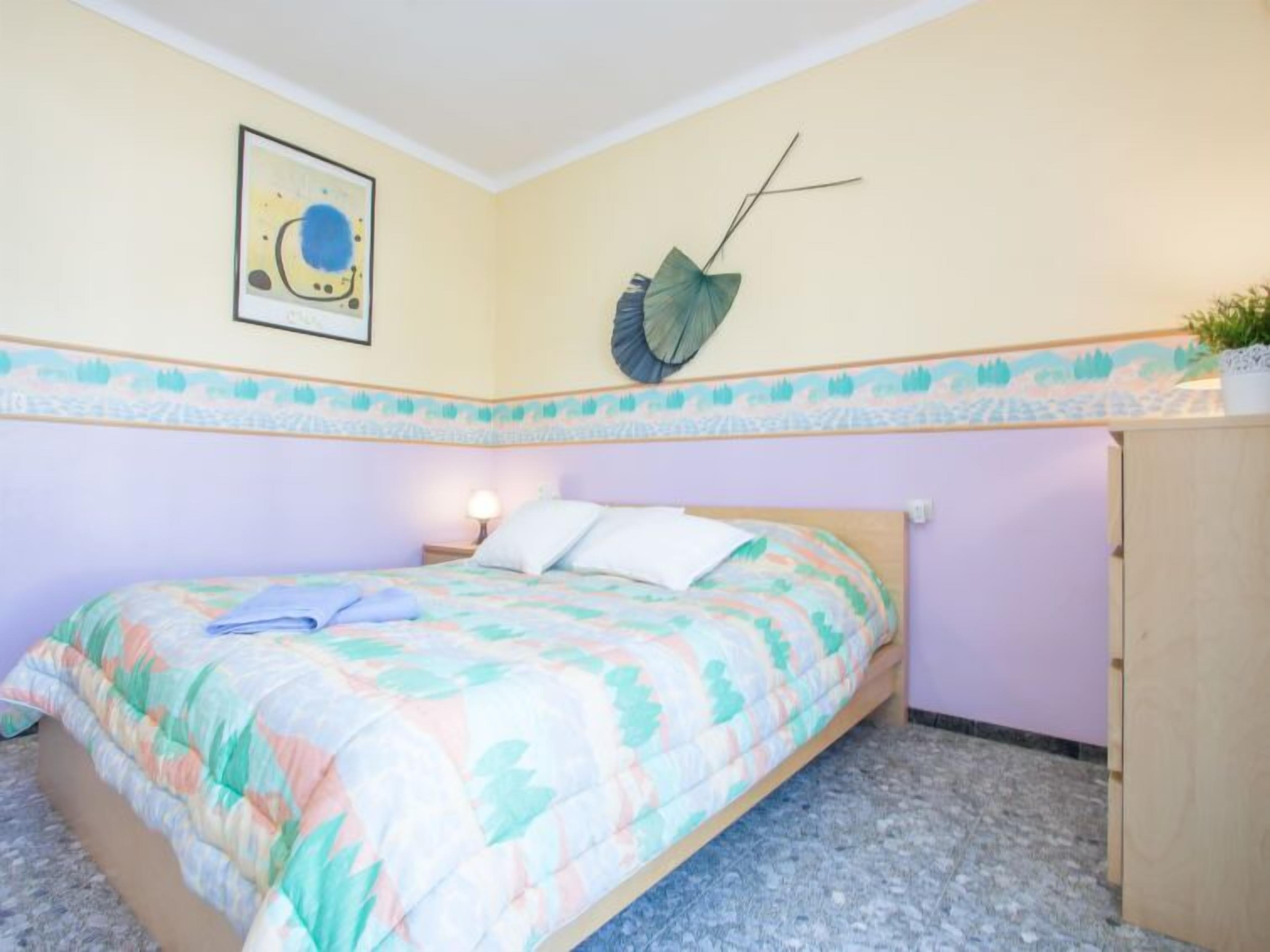 Una camera da letto con un letto, un comodino, una lampada, una decorazione a parete e un armadio.