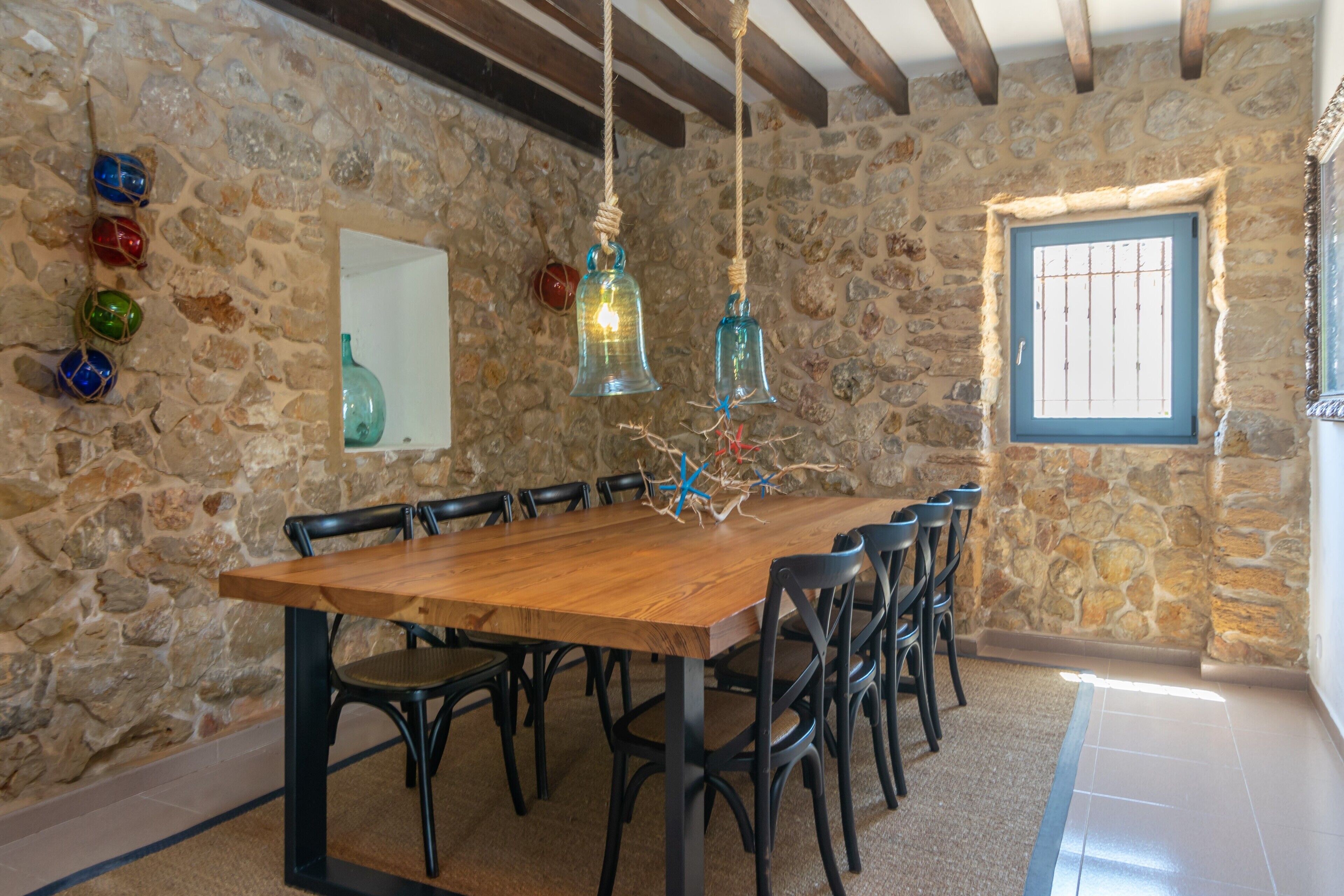 A stone-walled dining area with a wooden table and black chairs.