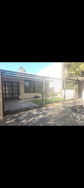 Contemporary building with a flat roof and large windows, set behind a secure metal fence.