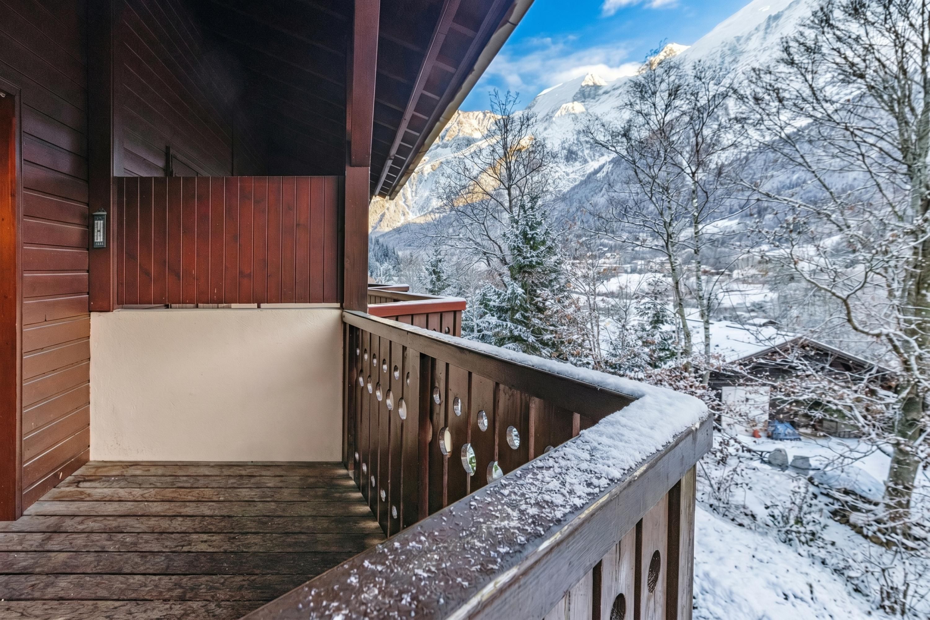 Un balcon en bois offrant une vue sur des montagnes enneigées.
