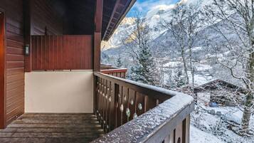 Een houten balkon met uitzicht op besneeuwde bergen.