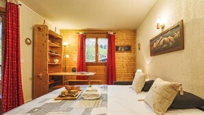 Una habitación acogedora con una cama, un estante de madera, una mesa con lámpara y una ventana con cortinas.