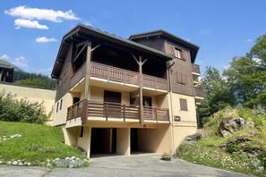 A multi-story building with balconies, a sign indicating a restaurant, and a parking area.
