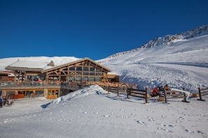 Una cabana de fusta amb un balcó que domina un pendent de muntanya cobert de neu.
