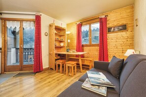 Una sala de estar acogedora con detalles de madera, un sofá, una mesa de comedor con sillas y una estantería.