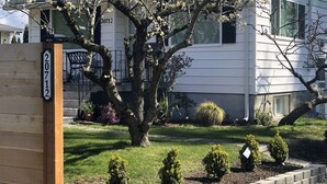 Ein Wohnhaus mit einem großen Baum, einem gepflegten Rasen und einem Hausnummernschild.
