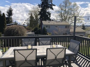 Une terrasse extérieure avec une table et des chaises, entourée d’une plateforme en bois et d’une rambarde en métal.