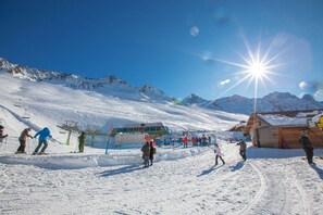 A ski resort with snow-covered slopes, a ski lift, and a wooden building.