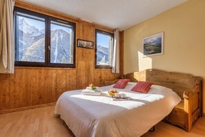 A bedroom with a wooden headboard, a bed with white linens, a window with a mountain view, and a framed picture on the wall. - Cham Sud G45 / 2-Min Walk to Centre, Chamonix, France (Chamonix)