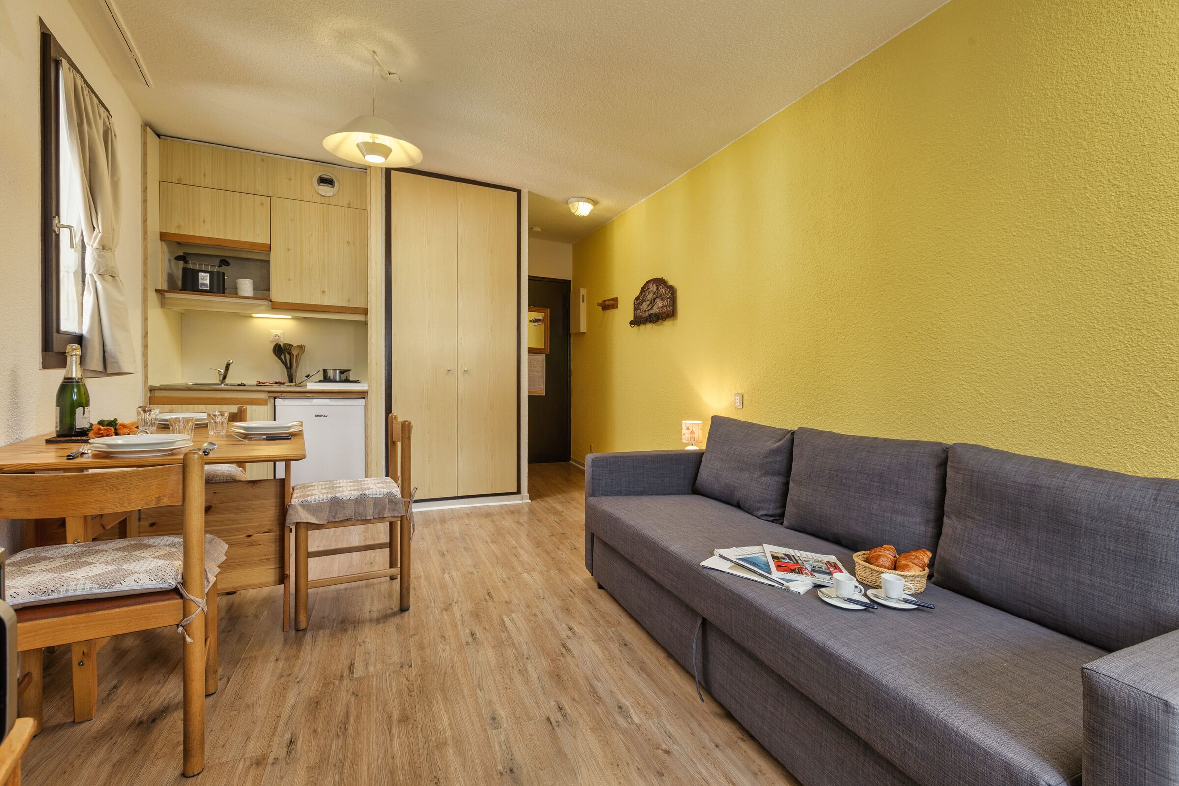 Un espace de vie compact comprenant un coin repas, une kitchenette et un canapé avec des articles pour le petit-déjeuner.