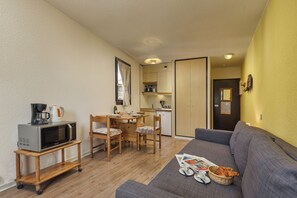 A compact living space with a kitchenette, a dining area, and a sofa.