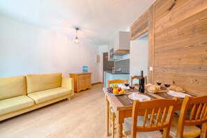 A compact living space with a sofa, dining table, and wooden accents.