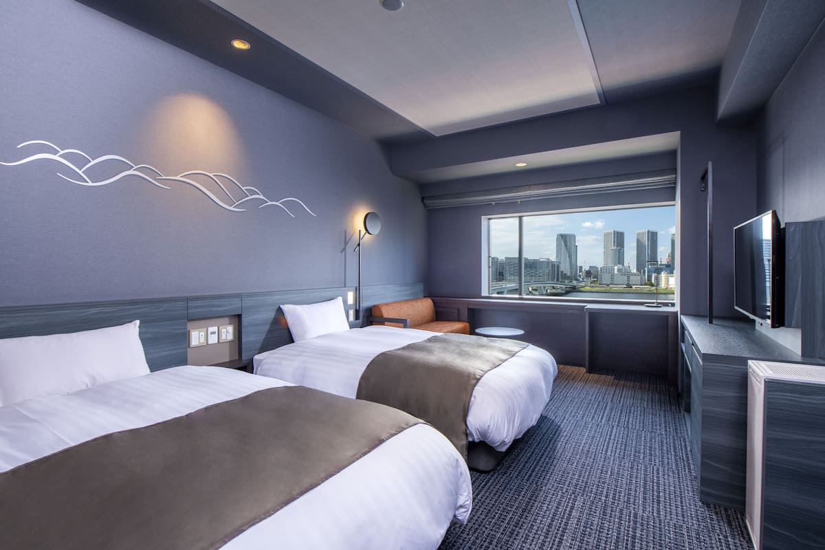 Habitación de hotel con dos camas, televisión, vistas a la ciudad y un diseño moderno.