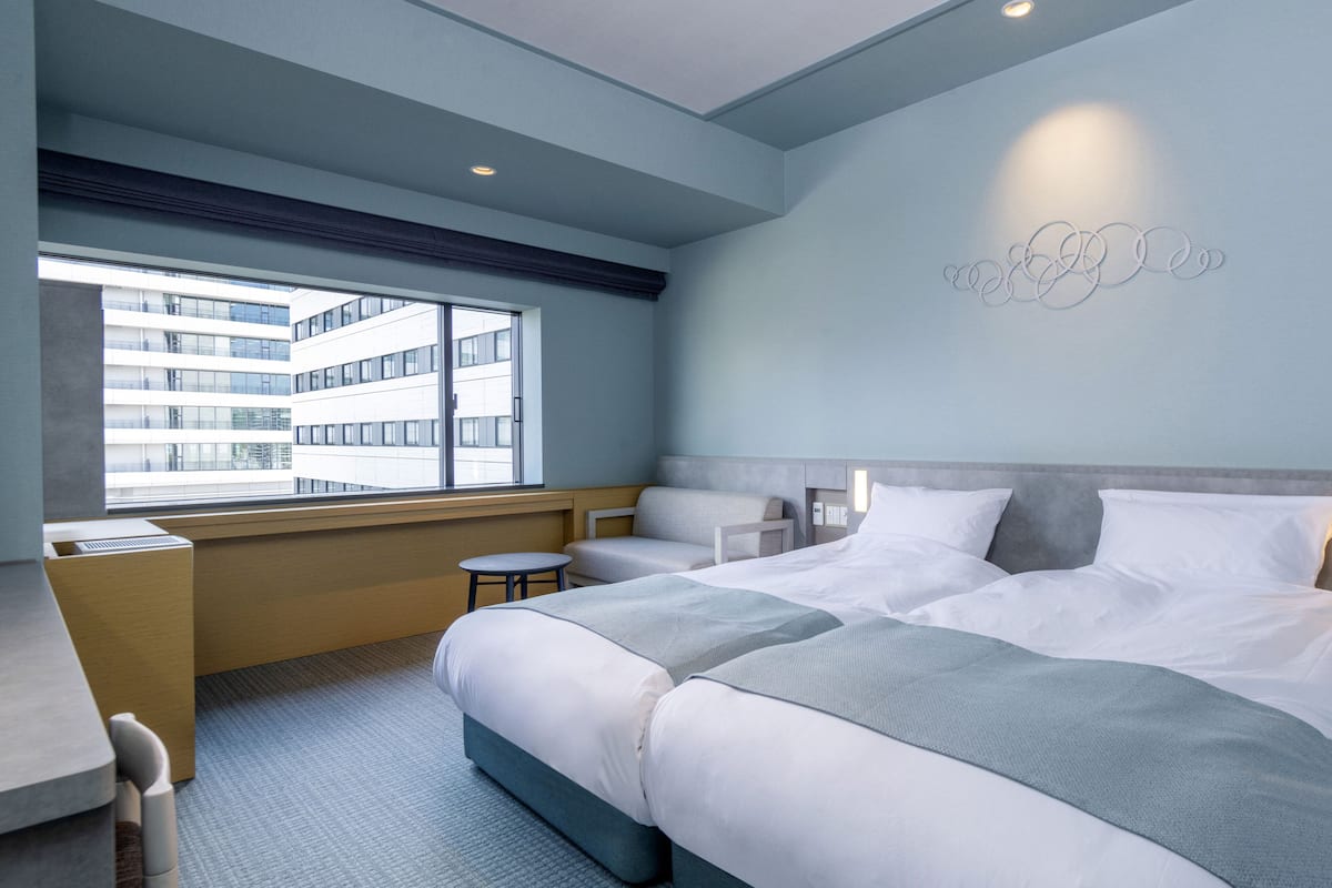 Habitación de hotel moderna con una cama grande, un escritorio y vista a un edificio a través de la ventana.