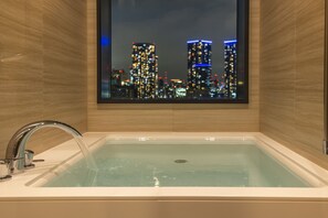 A modern bathroom with a bathtub, a window with a cityscape view, and a faucet.