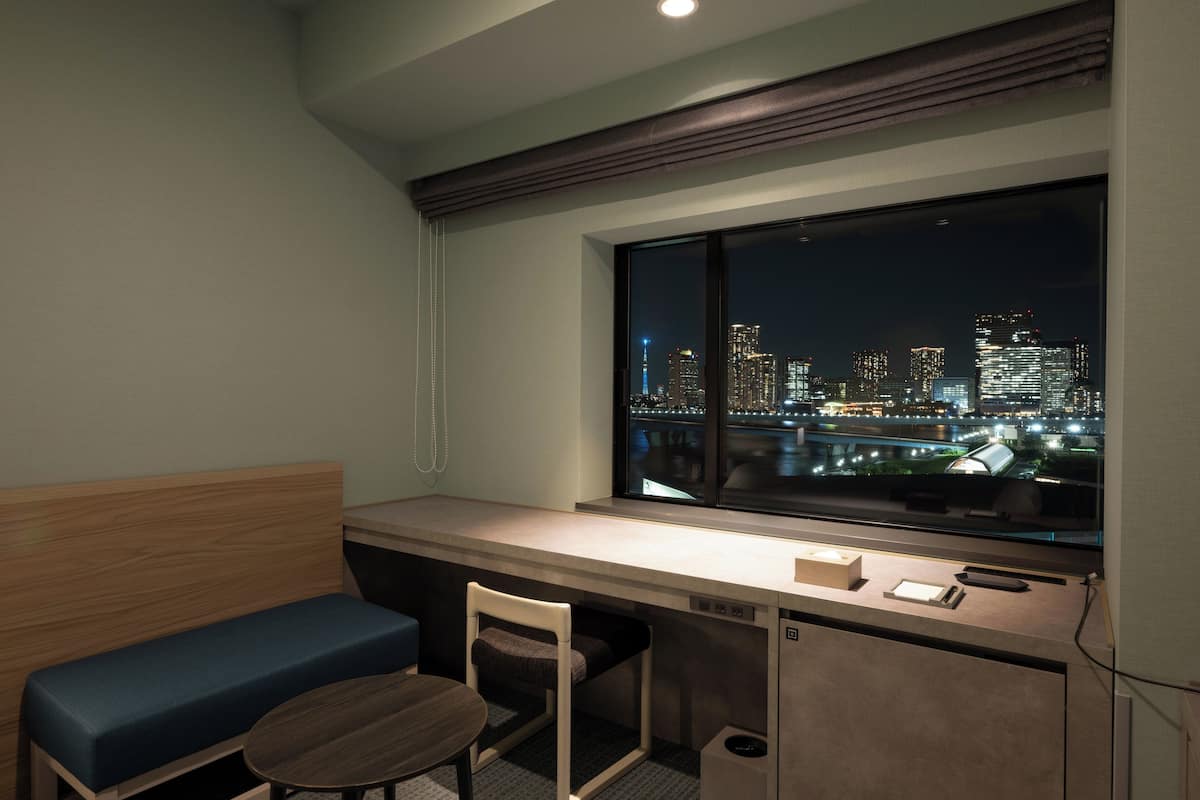 Habitación de hotel moderna con vista a la ciudad, un escritorio, una silla y una mesita.