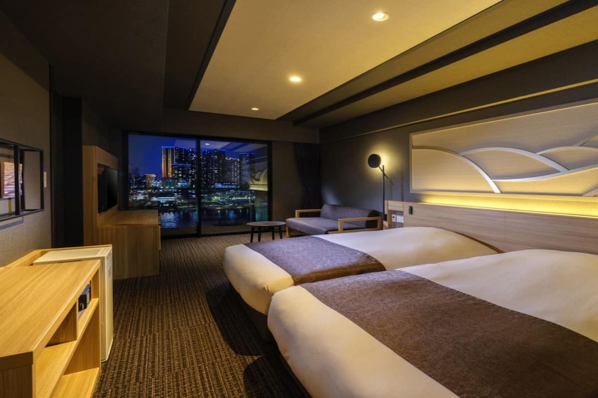 Habitación de hotel con vistas a la ciudad, dos camas, un escritorio y una silla.