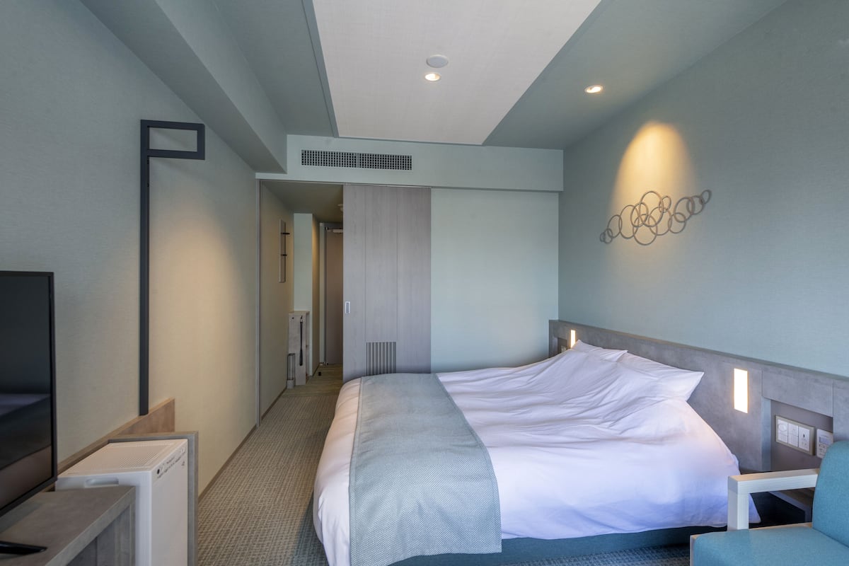 Una habitación de hotel moderna con una cama grande, un escritorio y un televisor.