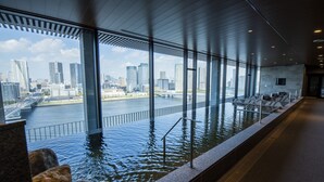 Une piscine à débordement intérieure offrant une vue sur la ville, de grandes fenêtres et une architecture moderne.