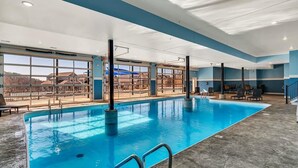 En inomhuspool med fri utsikt mot omgivningen, omgiven av sittområden och ett stort fönster.