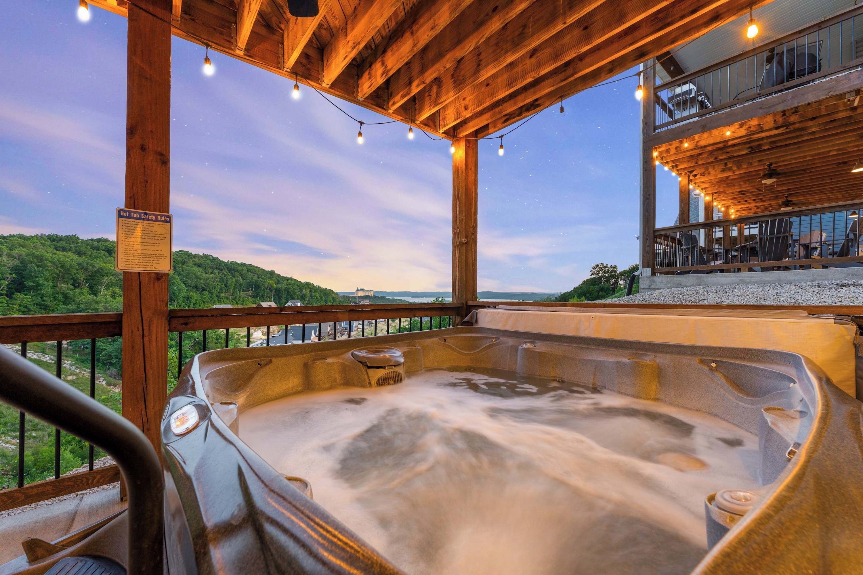 Een hottub met een houten terras, uitzicht op het landschap en een balkon met buitenmeubels.