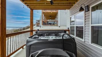 Relax on the deck with a hot tub overlooking a scenic landscape.