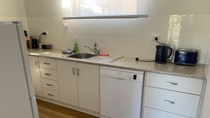 A modern kitchen with white cabinets, a Bosch dishwasher, a sink, and a window above the countertop.