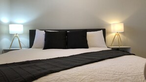 A neatly made bed with a black and white duvet, two bedside lamps, and a dark headboard.