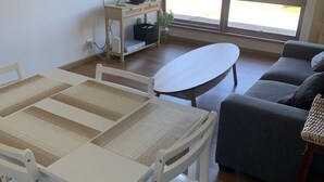 A living room with a dining table, a sofa, and a TV on a stand.