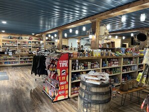 Interior de una tienda con estantes de madera llenos de aperitivos, bebidas y otros productos.