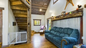 Ein geräumiger Wohnbereich mit einer Holztreppe, einem blauen Sofa und einem dekorativen Regal.