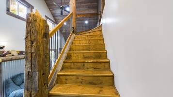 A wooden staircase with a handrail, a ceiling fan, and a window with blinds.