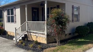 A single-story house with a front porch, a small front yard, and a red roof. - Lakefront Cabin in quiet cove. No steps to private boat slip. Pet friendly. (Jacksboro)