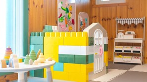 A play area with a table, a playhouse, and storage shelves. - Yeosu Hi Mom Kids Family Pension Black (Yeosu)