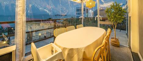 A dining area with a table and chairs, large windows with a view, and hanging lights.