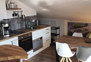 Een moderne keuken met een houten aanrecht, roestvrijstalen apparatuur en een eethoek met een houten tafel en stoelen.