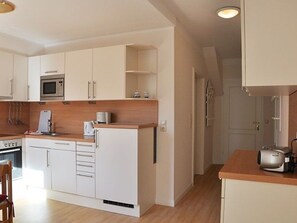 A compact kitchen with white cabinets, a microwave, a coffee maker, and a toaster.