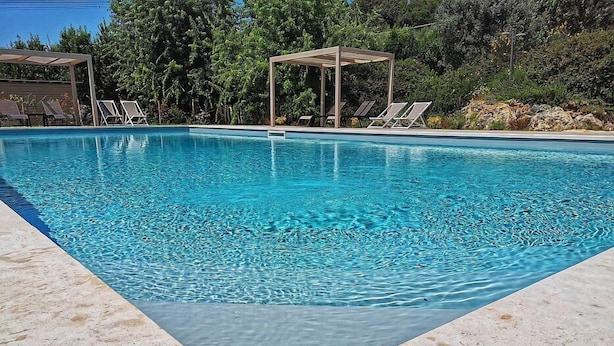 Una piscina rectangular con agua azul cristalina, rodeada por un solado de baldosas.