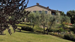 Una casa con techo inclinado, rodeada de césped cuidado y árboles.
