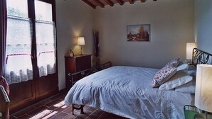 A bedroom with a bed, a desk, a chair, a lamp, and a painting on the wall. - Casa Raissa C: A characteristic and welcoming apartment that is part of a villa immersed in a splendid landscape, in a lovely little hamlet, with Free WI-FI. (Montaione)