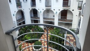 Un patio de varios niveles con balcones, plantas en macetas y un patrón de piso a cuadros.