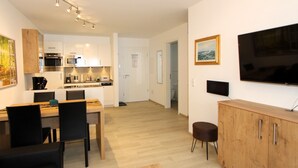 A modern apartment with a dining area, kitchen, living room, and a TV. - GRA-115 - South-facing vacation apartment with whirlpool - Residence Grafenmatt 1.2 (Feldberg (Schwarzwald))