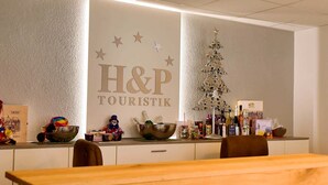 A reception area with a sign reading 'H&P TOURISTIK,' a decorative Christmas tree, and various items on the counter.