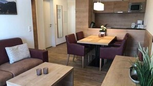 A modern living room with a sofa, a coffee table, and a dining area with chairs and a table.